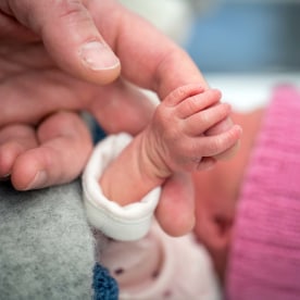 Newborn baby holding on to a finger